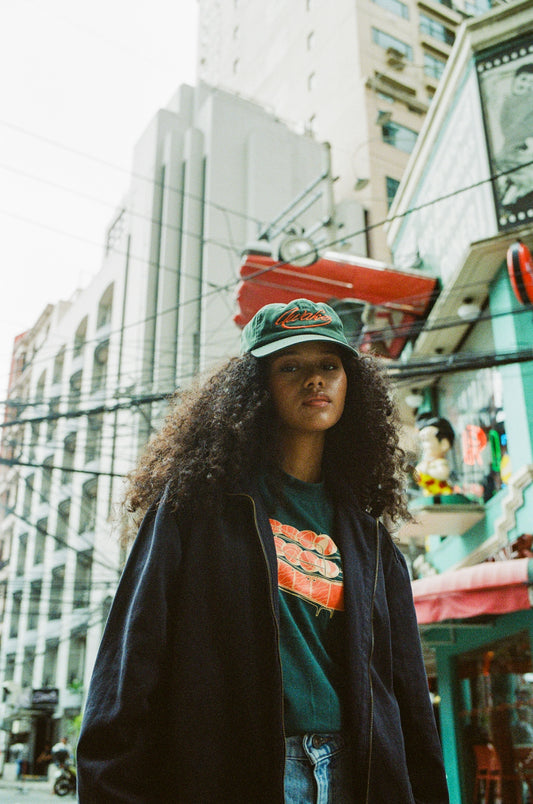A woman standing on a city street with a skateboard on her head