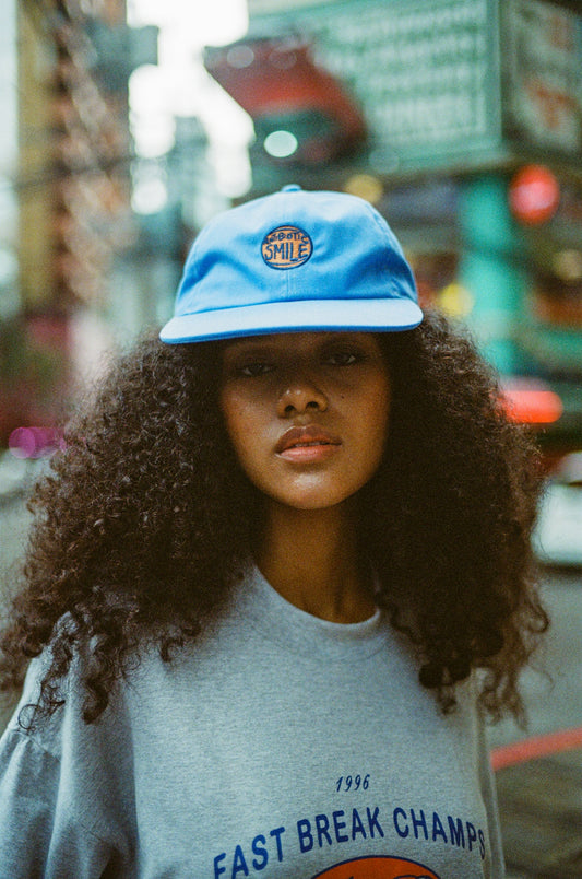 A woman with curly hair wearing a blue hat